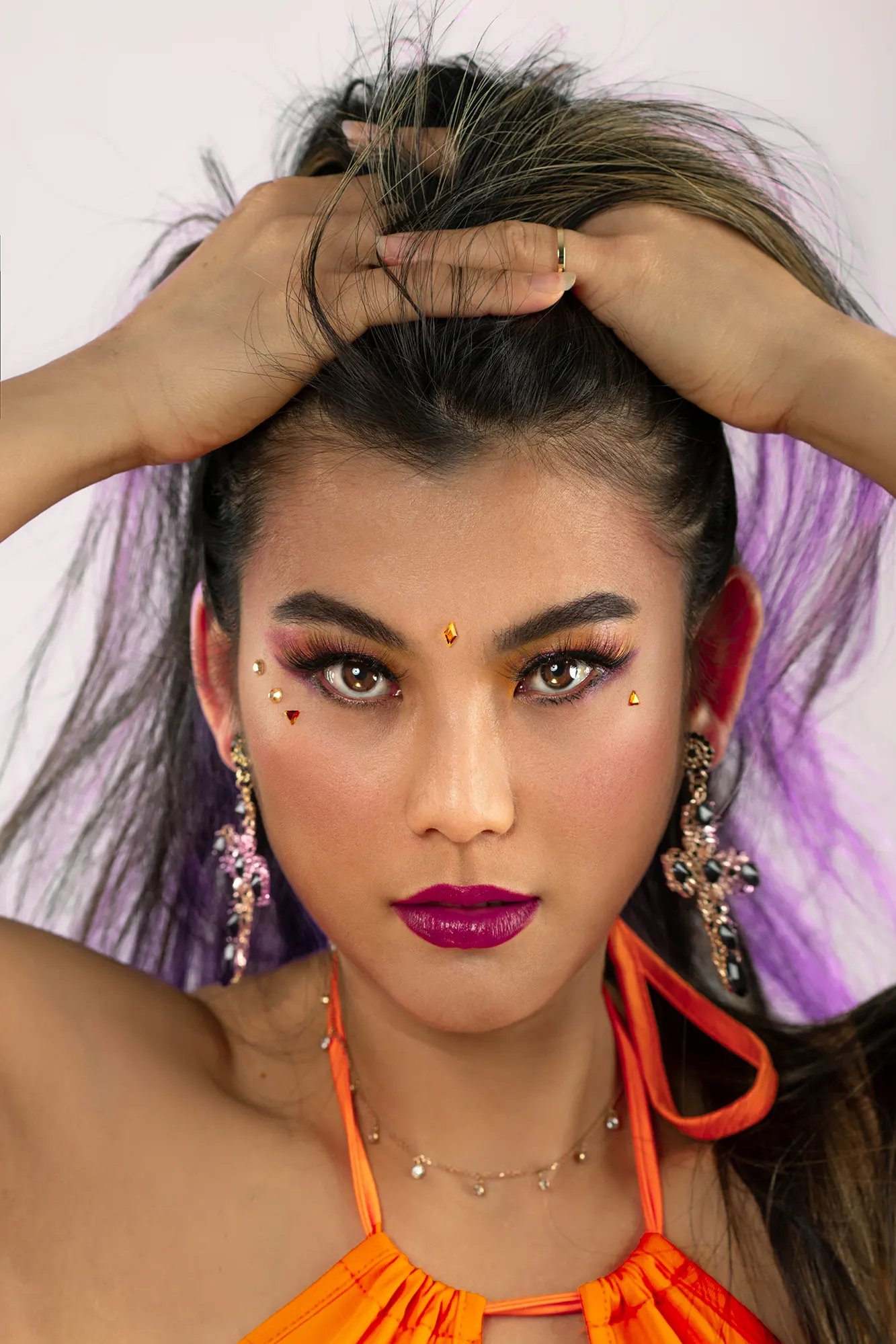 Stunning woman with bright makeup and bejeweled face showing high-end beauty portfolio quality